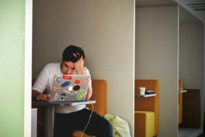 exhausted male founder wearing white top using MacBook