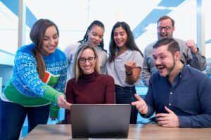 men and women sitting and standing while staring at laptop who aren't under pressure