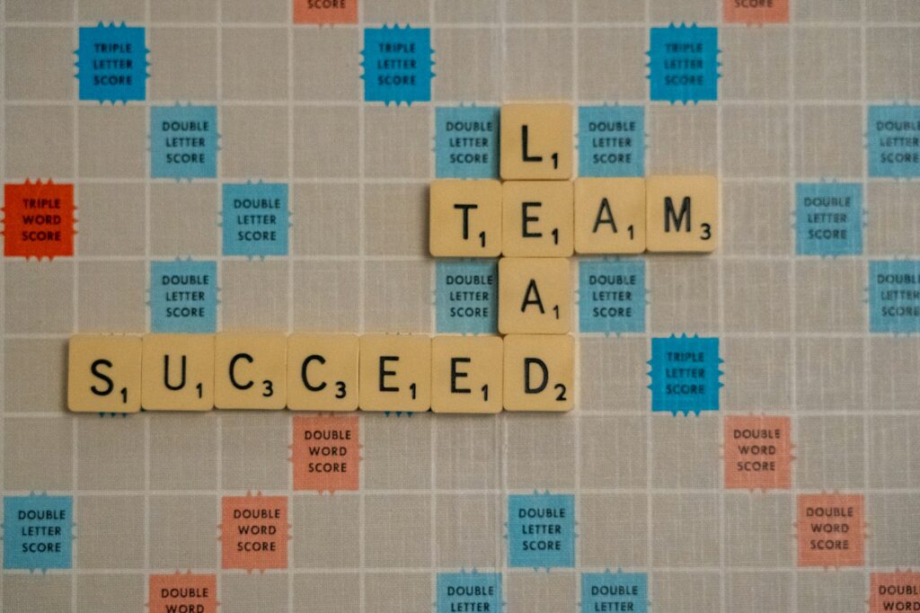 scrabble tiles with leadership behaviour words of lead, team and succeed