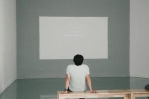 man under uncertainty stating at wall sitting on bench inside room