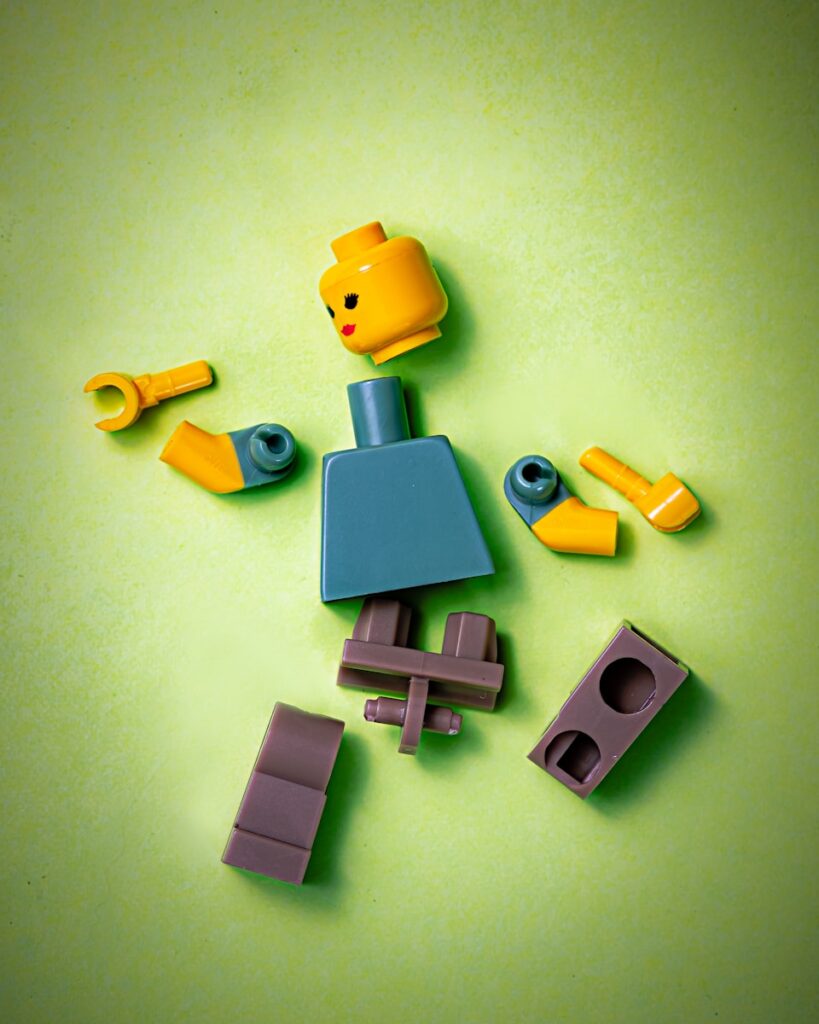 blue orange green and yellow lego man dismantled under pressure and force
