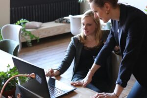 two women looking at a laptop on how to lead a startup